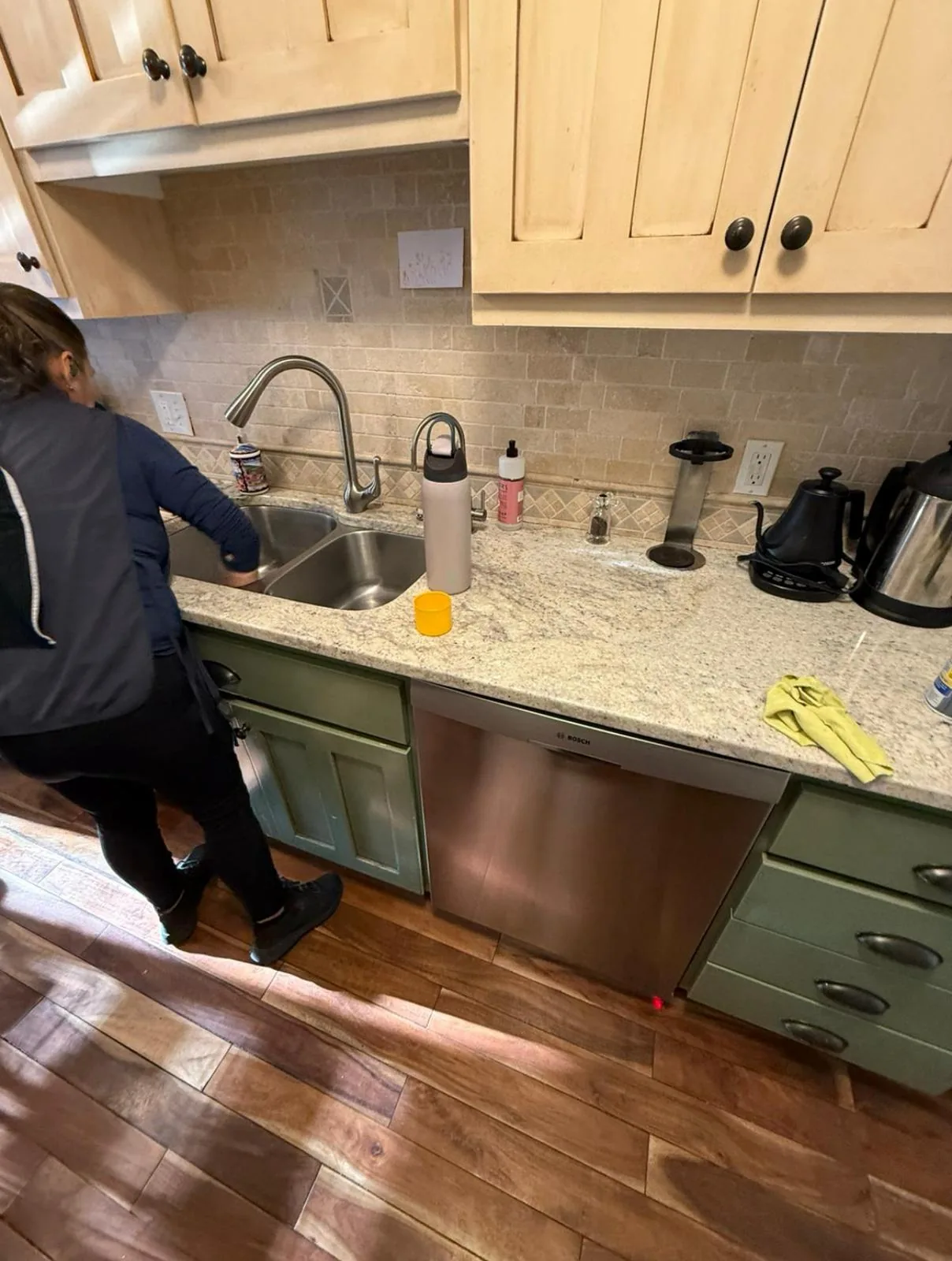 Clean Lean Services team member cleaning a kitchen sink and countertops