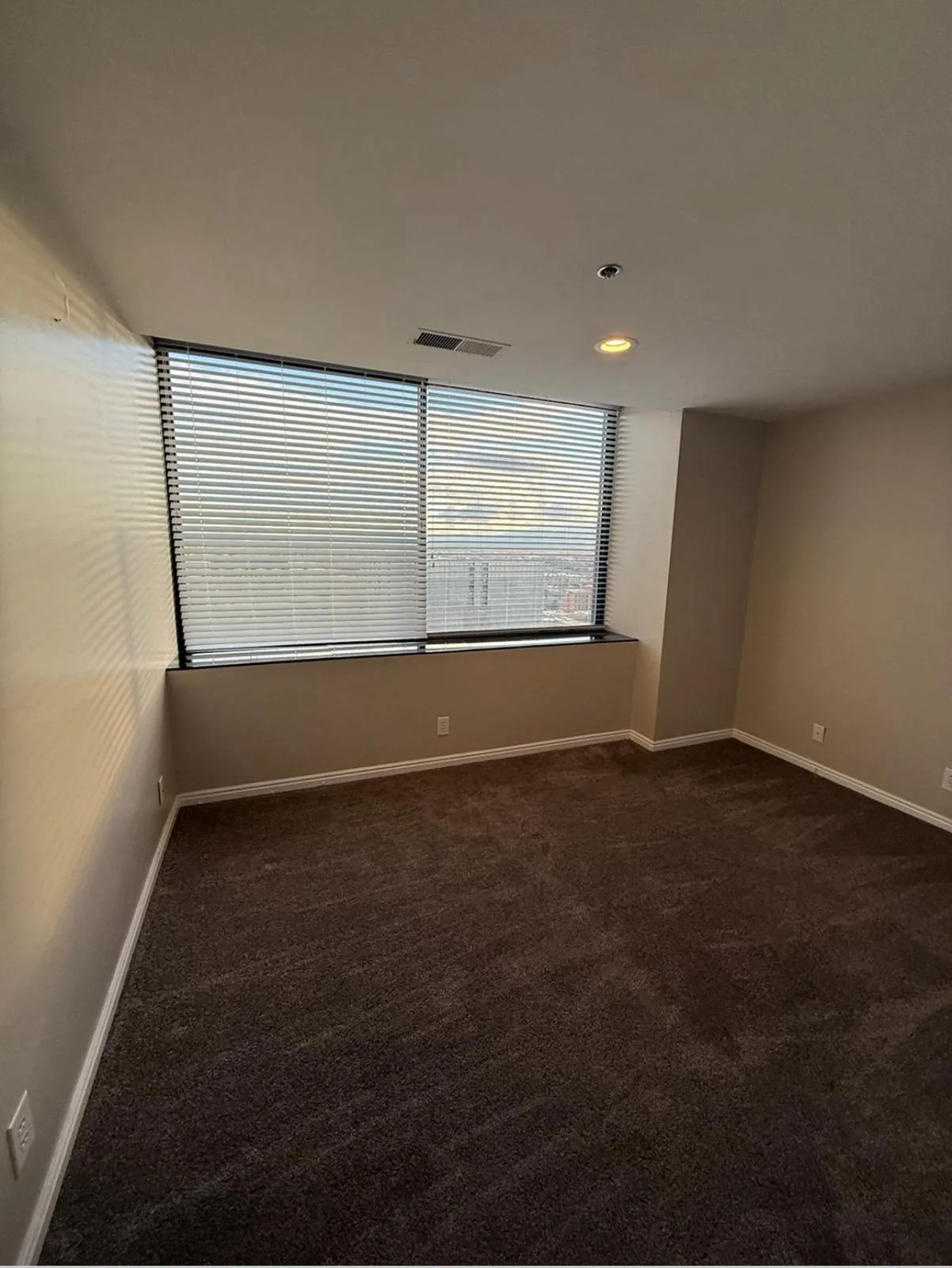 Empty bedroom with vacuumed carpet and clean window blinds after a move-out cleaning