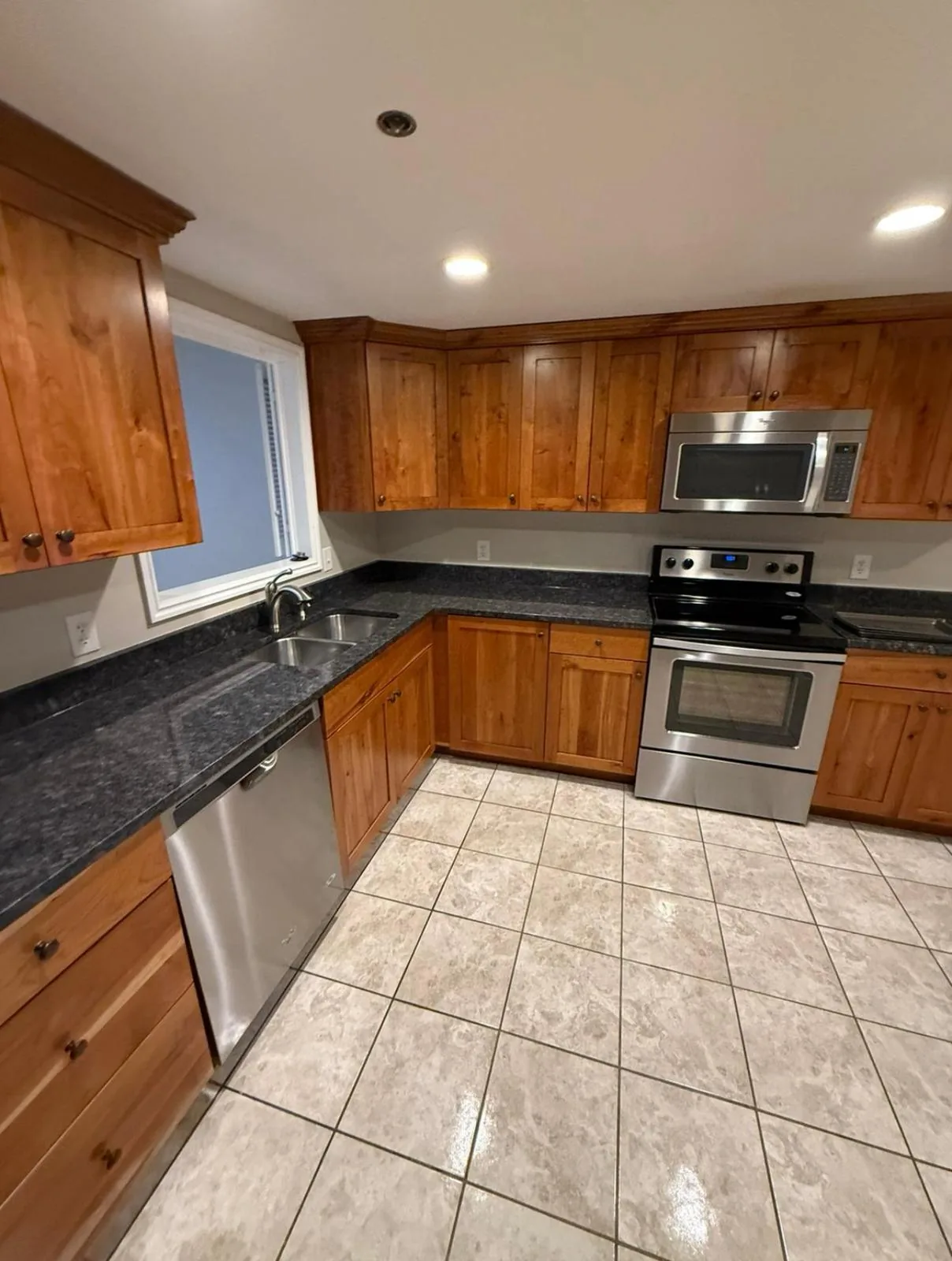 Clean kitchen with wood cabinets, granite counters and freshly mopped tile floor