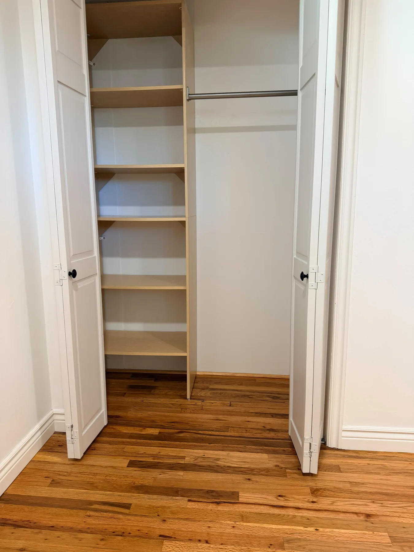 Neatly organized closet with clean wood shelves and hanging rod